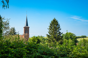 tower of church between green trees, Hunspach, France