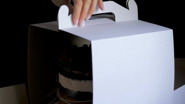 Female hands packs naked cake into paper cake box