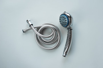 New set steel shower head sprayer with metal shower hose for the bathroom with power regulator on a gray background. The concept of home repair is the choice and replacement of plumbing.