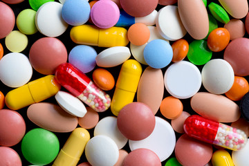 Different colorful pills and drugs background. Medicinal tablets, capsules and pills. Top view