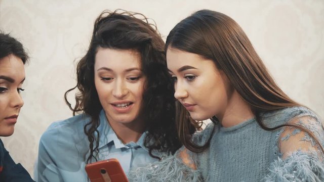 Happy diverse friends using phone together in cafe during lunch. Looking at smartphone screen. Laughing man showing funny video in social network. Online joke to colleagues at meeting. fun.