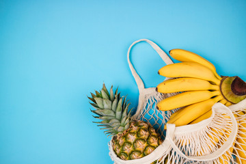 Shopping bag with organic banana and pineapple fruits on blue background. Shopping food with eco friendly bag. Caring for the environment, rejection of plastic, zero waste, recycling concept