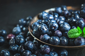 Juicy and fresh blueberries with green leaves on rustic table. Blueberry antioxidant. Concept for healthy eating and nutrition. Selective focus.