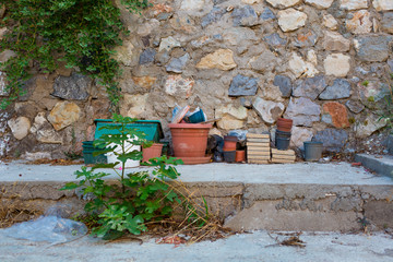 Fototapeta na wymiar Many old dirty flower pots stand near a stone wall in the backyard