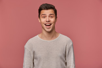 Portrait of cheerful handsome young guy wears in blank long sleeve, looks at the camera with happy...