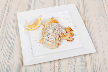 appetizing fried fish, beautifully laid out with greens and vegetables on a dish, for designer solutions in cooking	