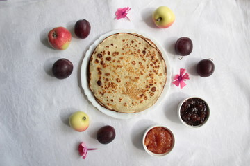 Pancakes, jam, fruits, flowers on white background