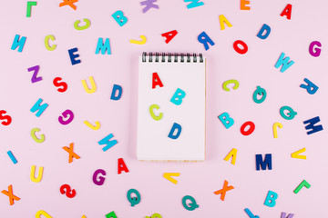 Back to school concept. Bright multicolored alphabet background. Colorful wooden letters on pink background. Isolated, Flat Lay, Copy space, top view