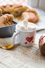 Christmas cookied and cakes with a mugs full of marshmallows, preparation of cokies and cakes for christmas, arranged on a tabletop with christmas decoration