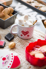 Christmas cookied and cakes with a mugs full of marshmallows, preparation of cokies and cakes for christmas, arranged on a tabletop with christmas decoration