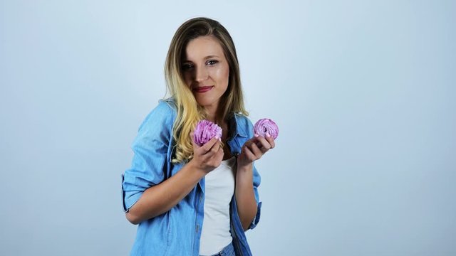 young beautiful woman smiling biting piece of delicious cupcakes on isolated white background