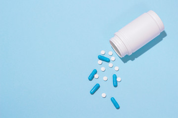Blue and white medicine painkillers, tablets and capsules and bottle. Copy space for text on blue background 