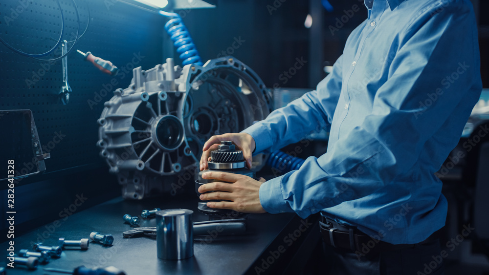 Fototapete professional automotive engineer in glasses is working on transmission gears in a high tech innovati