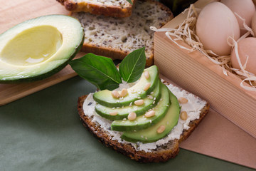 Top view of avocado toast with sesame and nuts on a wood cutting board