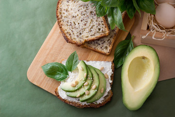 Vegan sandwich with avocado on green craft paper, top view