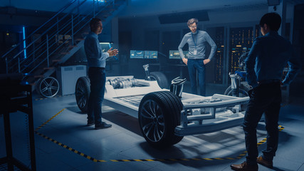 Diverse Team of Automobile Design Engineers Working Automotive Innovation Facility on Electric Car Platform Chassis Prototype that Includes Wheels, Suspension, Hybrid Engine and Battery