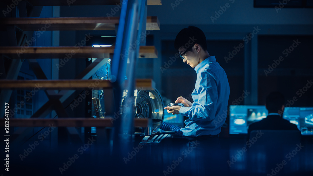 Fototapete Professional Automotive Engineer in Glasses is Working on Transmission Gears in a High Tech Innovative Laboratory with a Computer Screens.