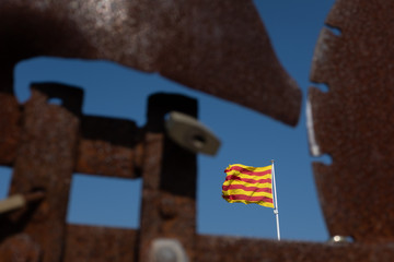 A worn Catalan flag visible through a rusted metal weather vane at the top of Begur Castle, Catalonia, Spain