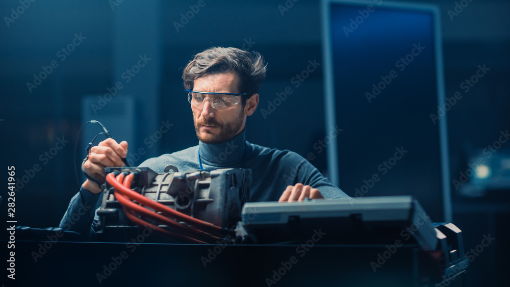 Leinwandbilder professional automotive engineer in glasses with a computer and inspection tools is testing an used 