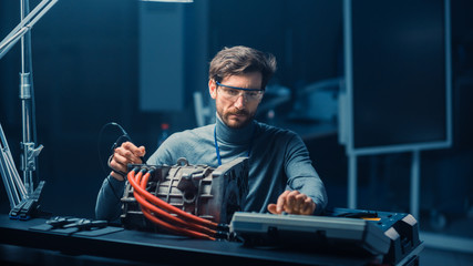 Professional Automotive Engineer in Glasses with a Computer and Inspection Tools is Testing an Used...