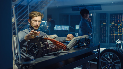 Professional Automotive Engineer in Glasses with a Computer and Inspection Tools is Testing an Used...