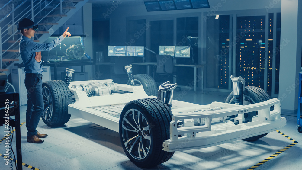Poster automotive engineer working on electric car chassis platform, using augmented reality headset and ma