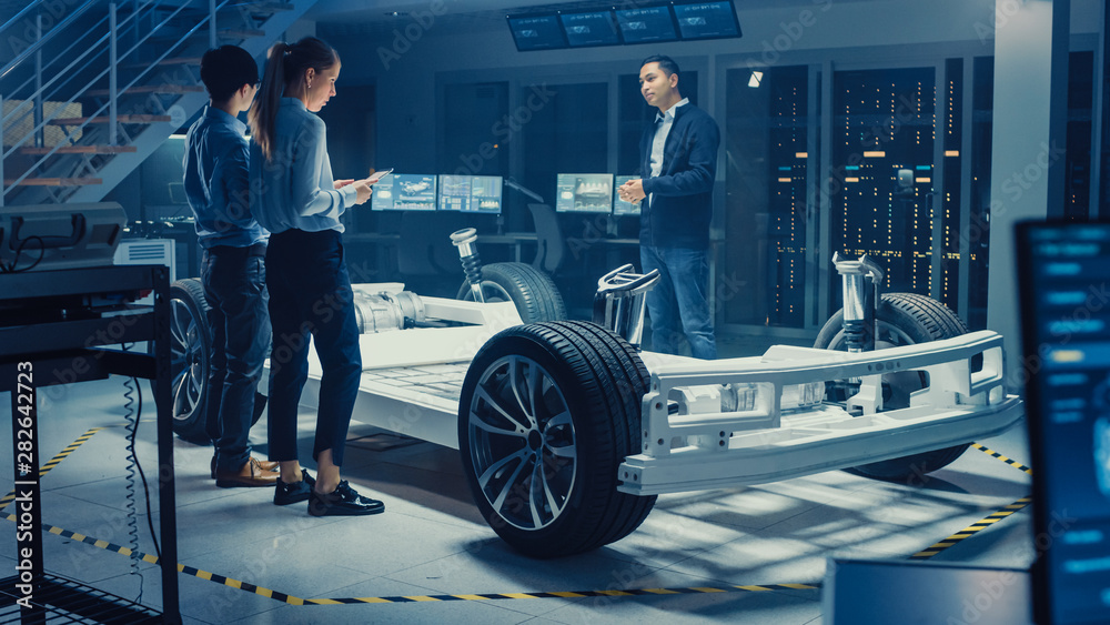 Aufkleber automotive design engineers talking while working on electric car chassis prototype. in innovation l