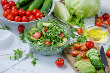 Fresh salad with cucumbers, cherry tomatoes, arugula, avocado, baby corn on white background. Vegetables on wood. Bio Healthy food, herbs and spices. Organic vegetables on wood.