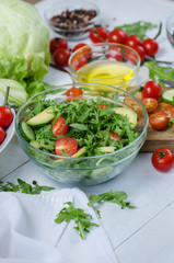 Fresh salad with cucumbers, cherry tomatoes, arugula, avocado, baby corn on white background. Vegetables on wood. Bio Healthy food, herbs and spices. Organic vegetables on wood.