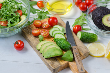 Fresh salad with cucumbers, cherry tomatoes, arugula, avocado, baby corn on white background. Vegetables on wood. Bio Healthy food, herbs and spices. Organic vegetables on wood.