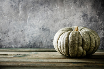 Autumn background with pumpkin on wooden tabel against old rust condition vintage wall