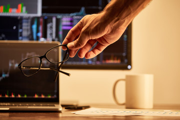 cropped view of adult man holding glasses in office