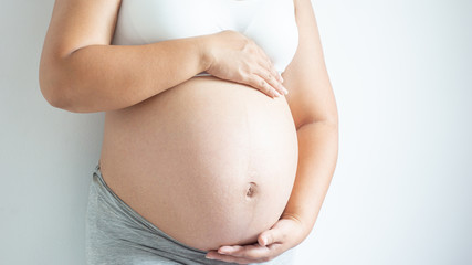 Close up of pregnant belly,woman holds her hands on her swollen belly.Medical exam concept,