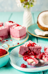 Raw vegan cakes volcanoes made from fermented cashew mousse, with raspberry jam, decorated with coconut flakes and sublimated raspberries. Gluten-free, no eggs. Healthy eating concept.