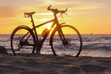 Fototapeta premium Bike and sunset by the sea. Black bike by the sea.