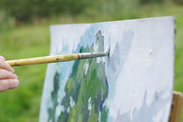 Drawing oil paintings of a natural landscape on a white cardboard