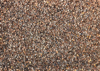 Rough unshelled buckwheat groats textured background pattern for your design, flat lay, from above overhead top view, closeup, macro