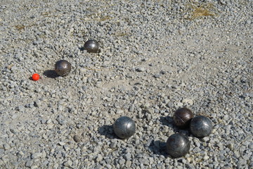 Parie de pétanque. Boules d'acier sur gravier. Cochonnet rouge. 