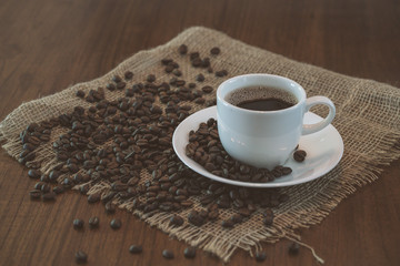 Hot coffee cup with coffee beans on wood table