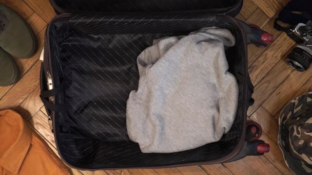Man hands are fast packing suitcase for a journey. Man dreams about travell. Summer clothing, pasport with money and diving mask with snorkel. Top view
