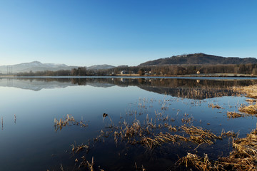 Incredible mirror on water surface on water dam near Frydek-Mistek, czech republic. Sunrise on Olesna dam. Reservoir with blue sky and some mountains