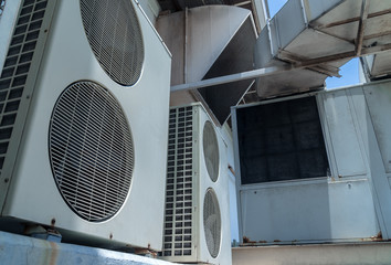 Low view and shade. The Old air conditioning cabinet with two blades. Placed beside the wall of building. And the large ventilation pipe attached to factory.