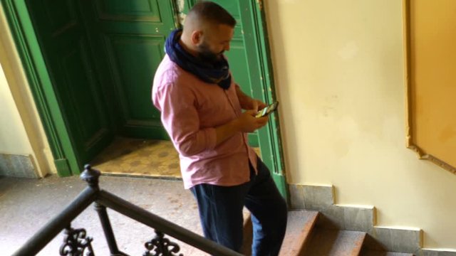Young man texting on smartphone walking on stairs
