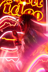 Portrait of woman with silver jacket and sunglasses in neon lights