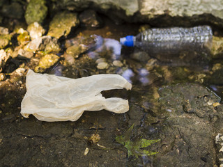 Plastic bag and water bottle near stream
