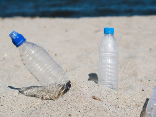 Empty plastic water bottle on sand at beach