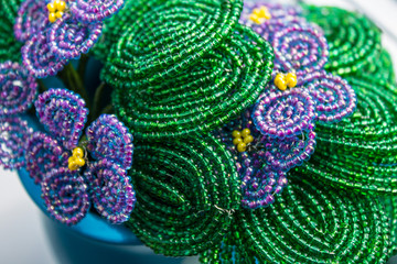 Bouquet of violets woven from beads in a blue ceramic vase