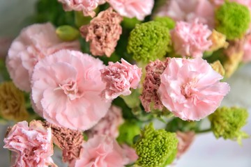 Withering bouquet with wilted carnations and green chrysanthemums with selective focus and blurred petals on front. Fading bouquet of flowers with pink and green flowers. Dying bouquet of flower