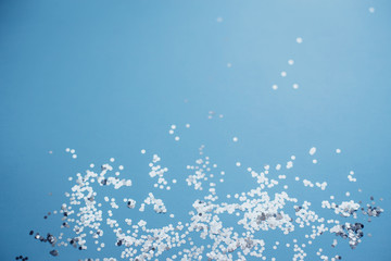 Abstract blue background with silver confetti close up.