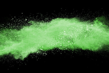 Green powder explosion on black background.